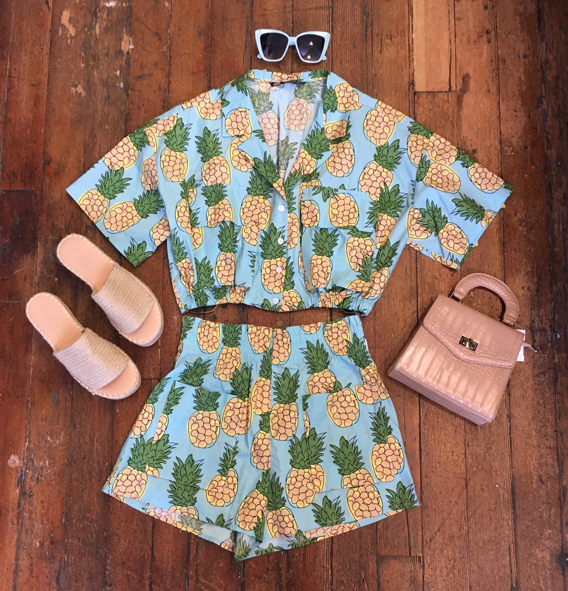 pineapple printed two piece shirt and short set, paired with oversized sunglasses, pink slide sandals and pink top-handle purse