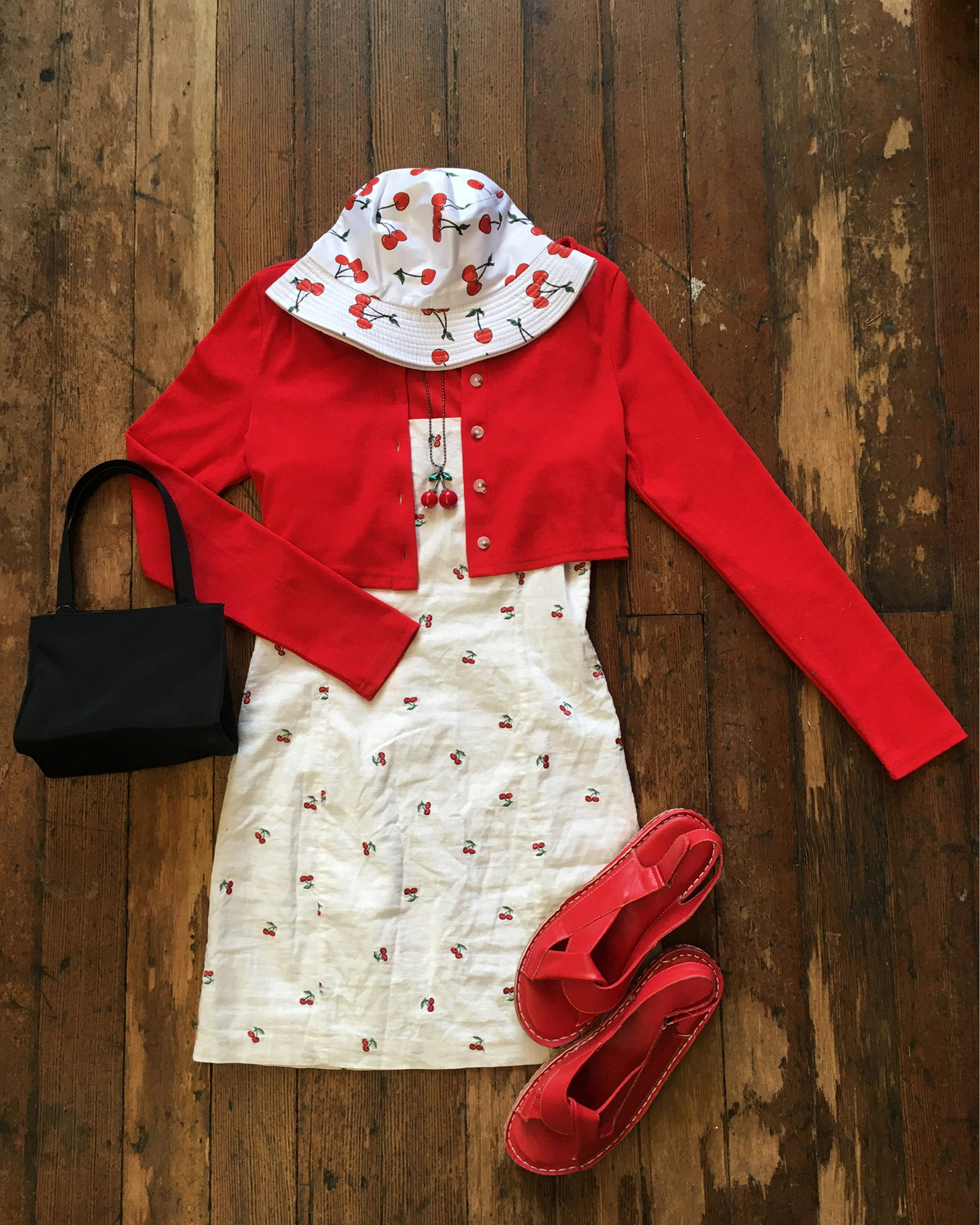 cherry-printed dress, cropped red cardigan, red sandals, black handbag and cherry printed bucket hat