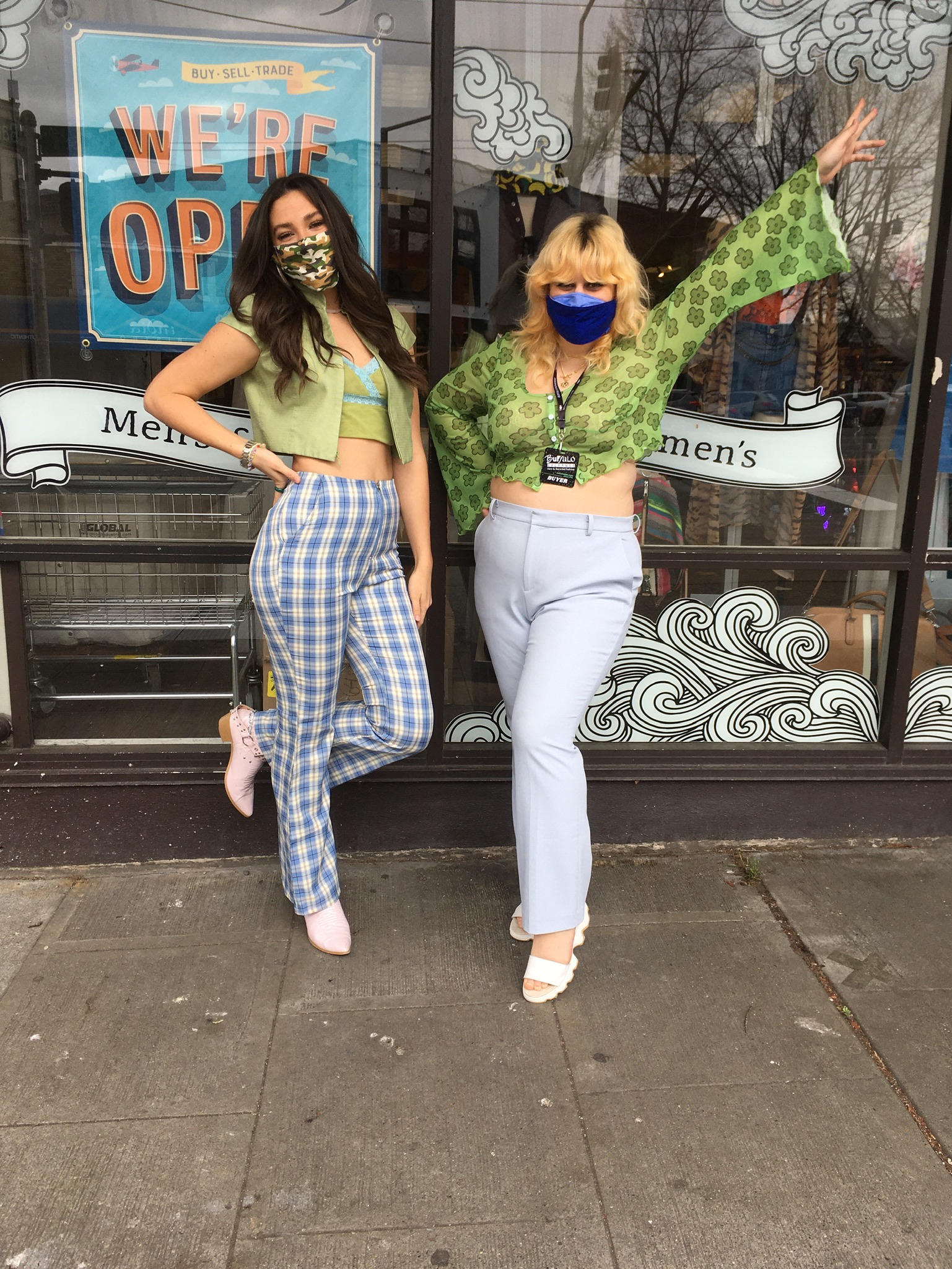 two people standing outside of store front, one wearing checkerprint denim and a coordinating camisole and cardigan set. the other wears a green mesh long sleeved top and lightwash denim