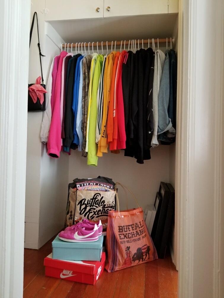 Neatly organized closet with hanging clothing, shoe boxes and Buffalo Exchange tote bags
