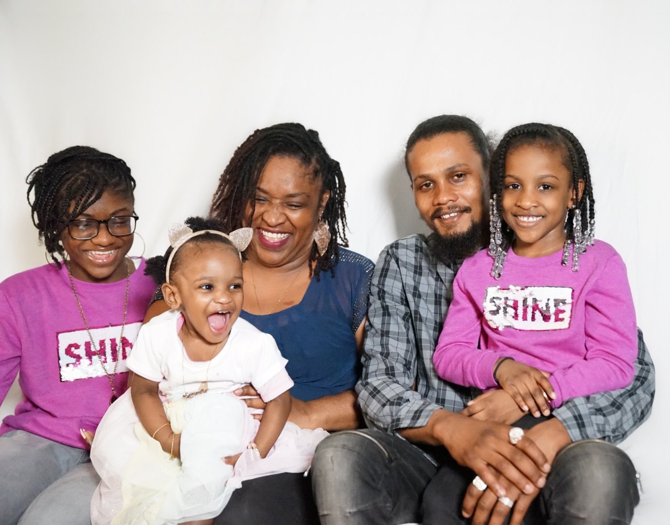 A family of 5 sitting close to each other and smiling