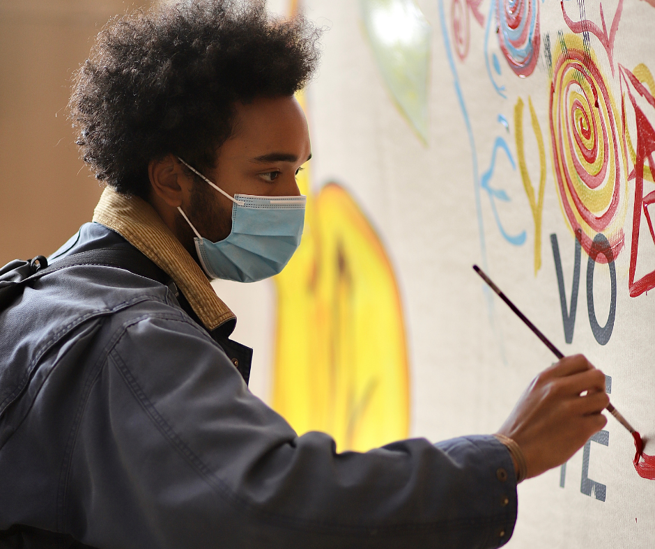 A man painting a large colorful mural