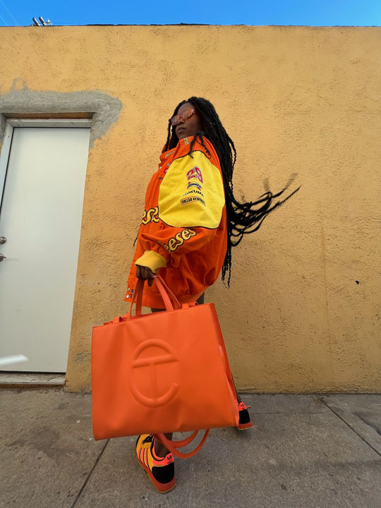 Woman posing with an oversized orange Telfar bag