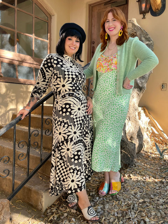Two women posing together wearing vintage-inspired floral dresses