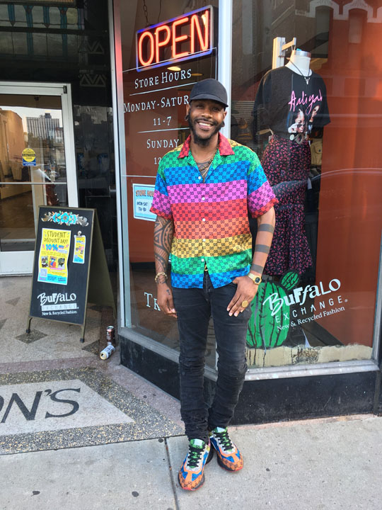 A man posing in front of Buffalo Exchange Pittsburgh wearing a rainbow Gucci shirt