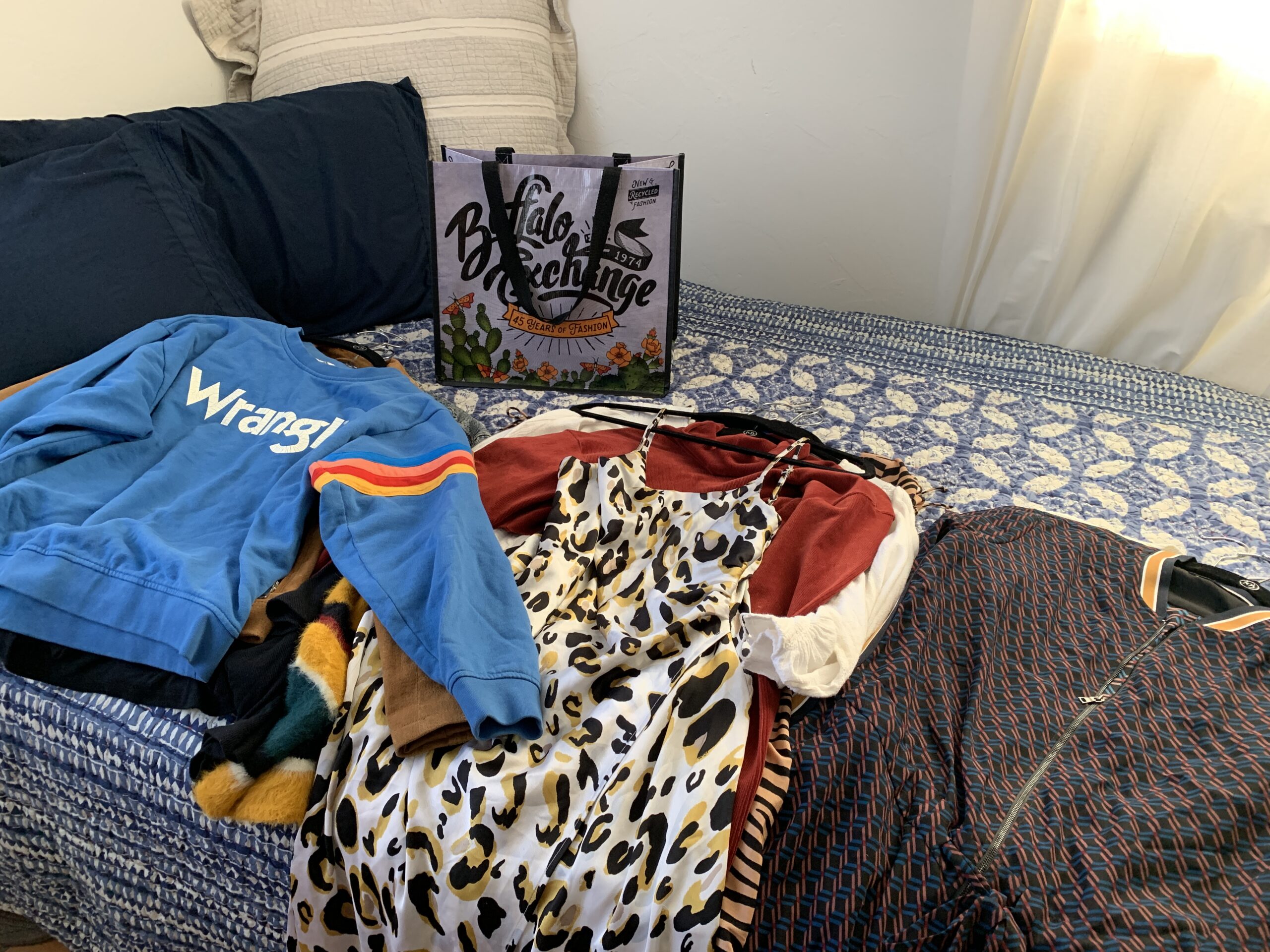 clothes on bed with Buffalo Exchange bag