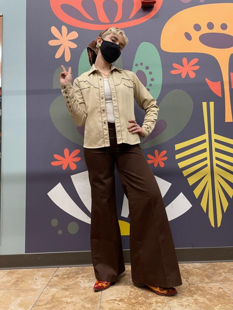 Celia posing in front of a colorful wall wearing an all brown look