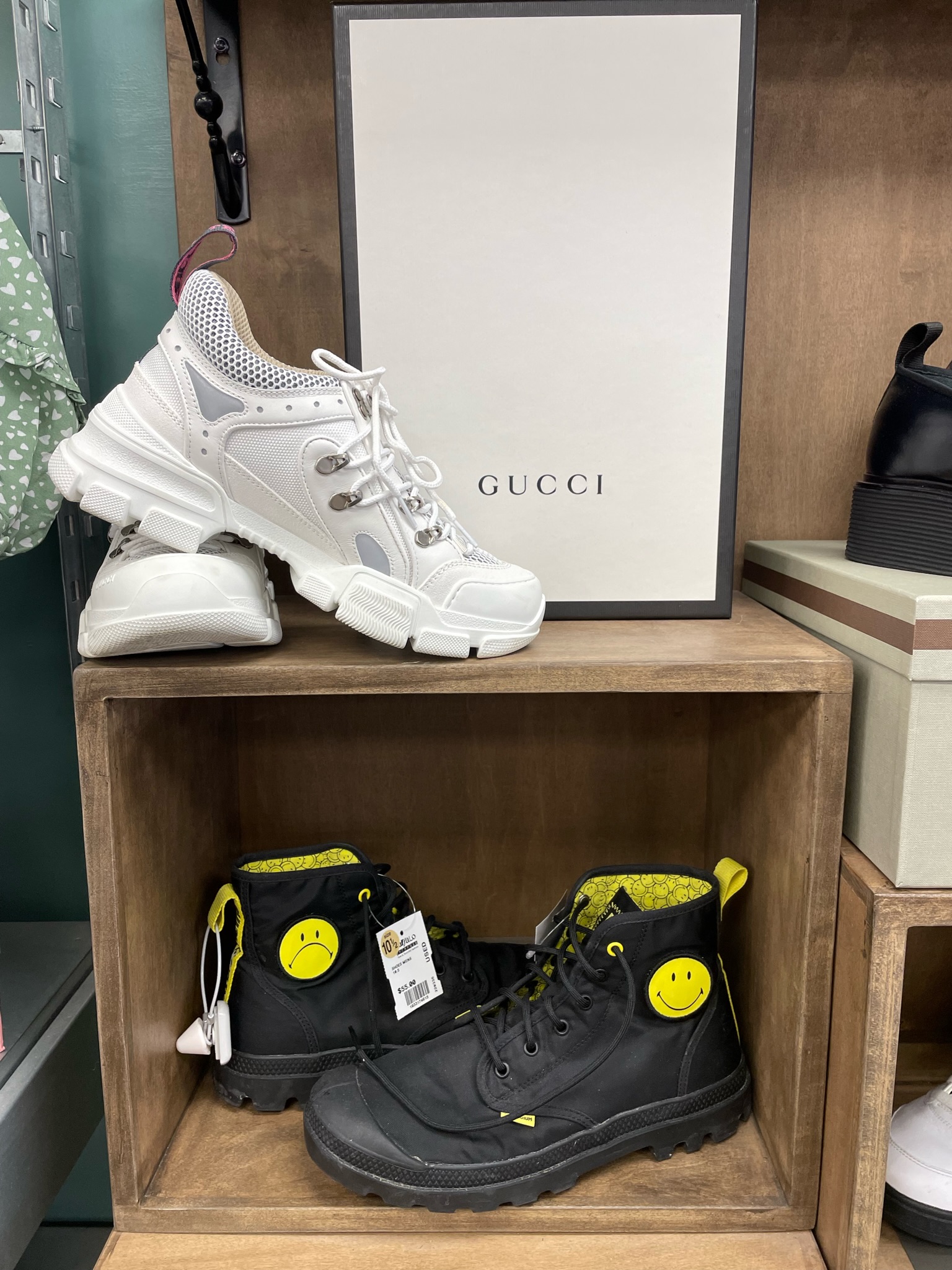 Closeup of wooden display holding white platform Gucci Sneakers and black Palladium lace up boots