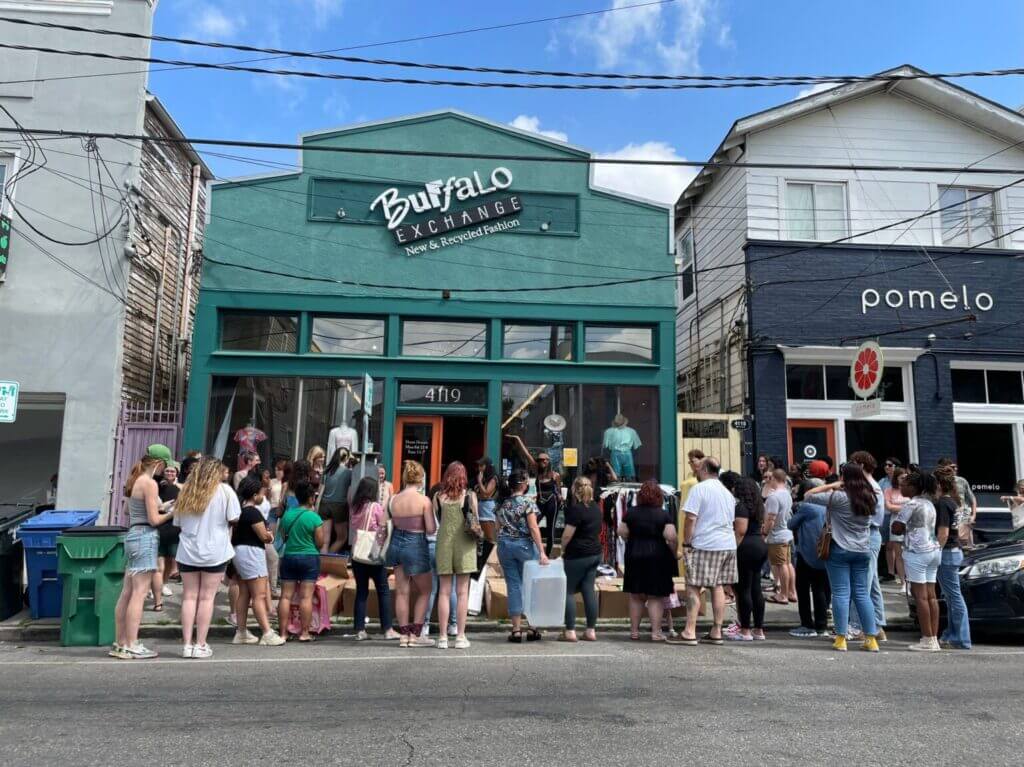 Crowd of people standing in front of Buffalo Exchange New Orleans's teal exterior