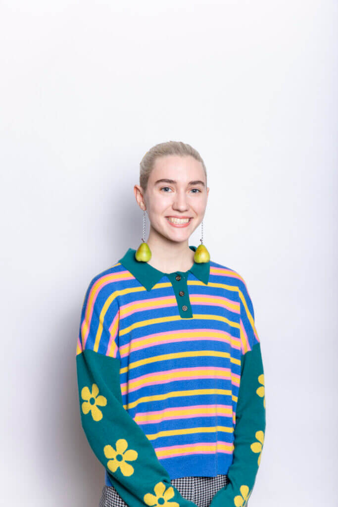 Headshot of Celia, she is smiling and wearing a colorful striped polo shirt