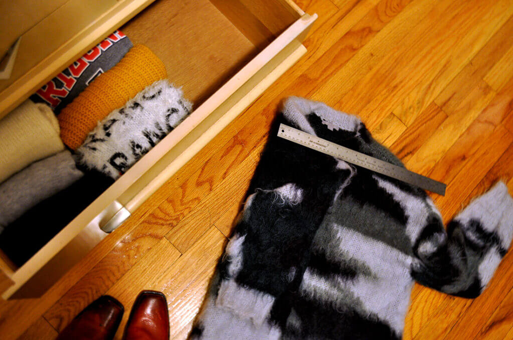 Sweater on the ground with a ruler placed on top of it