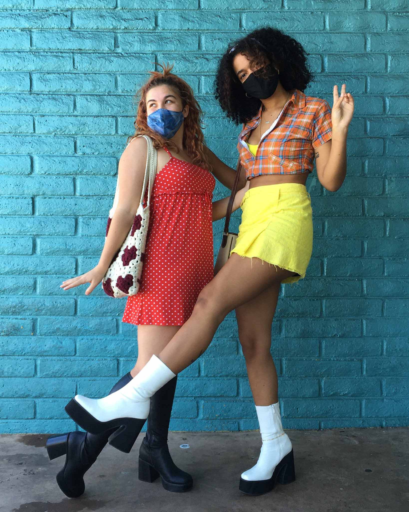 Person wearing platform black boots with red polka dot dress (left) and person wearing platform white and black boots with yellow skirt and plaid crop top (right)
