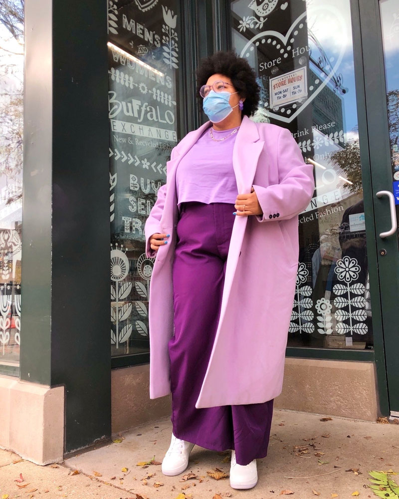Person standing in shop front wearing all-purple outfit