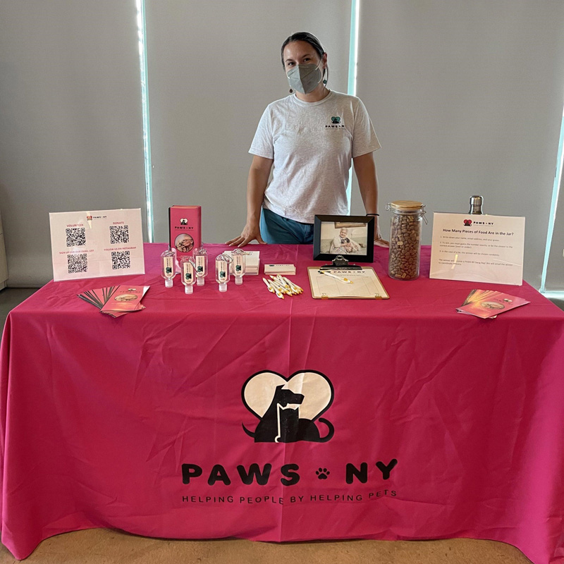 Person standing behind a table with informational materials about PAWS NY.