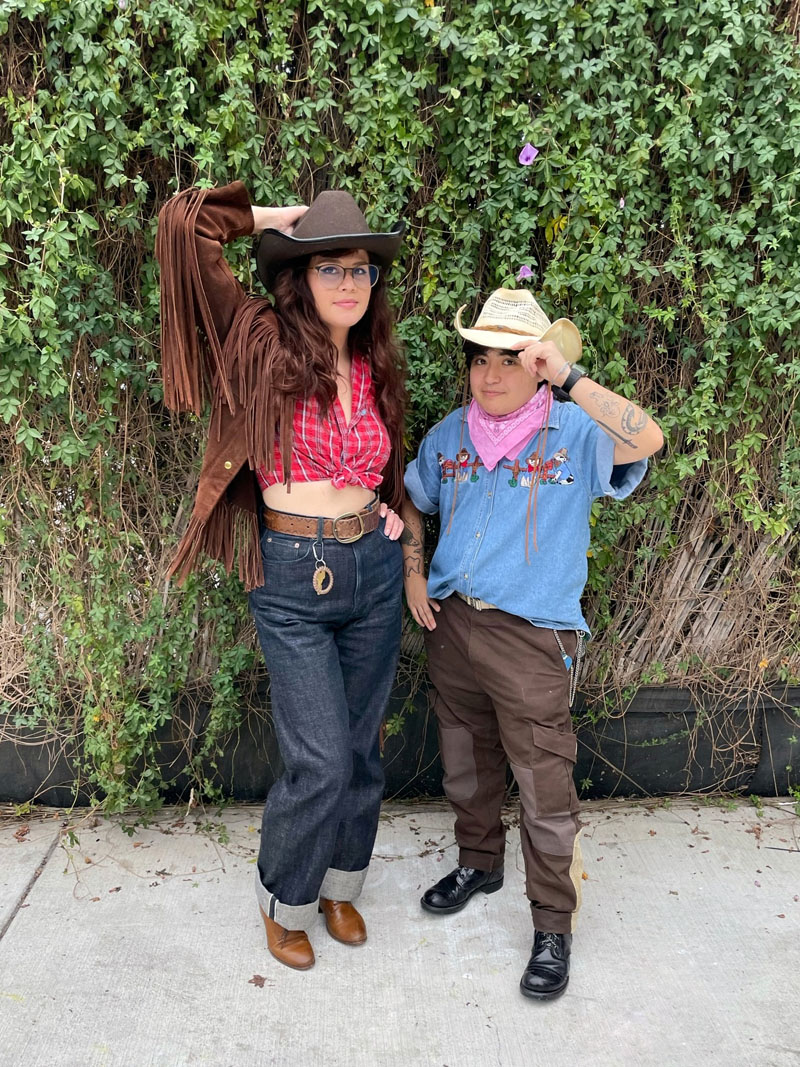 Two people in cowboy gear wearing cowboy hats, denim, and western boots.