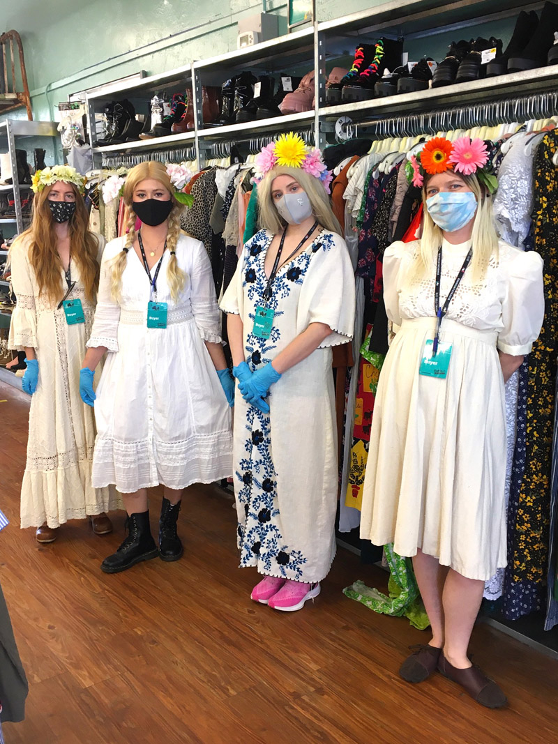 A group of people dressed as the cult from the movie Midsommar, all wearing white, mid-length dresses and flower crowns.