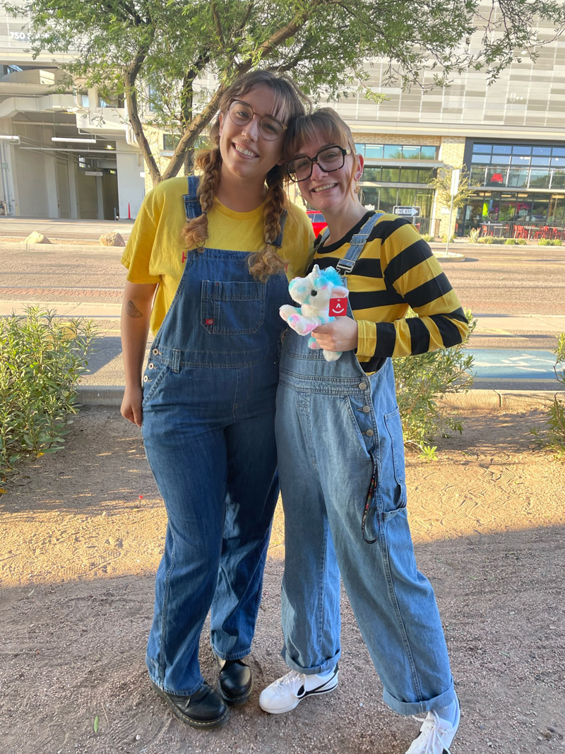 Two people dressed as Minions wearing yellow t-shirts under denim overalls.