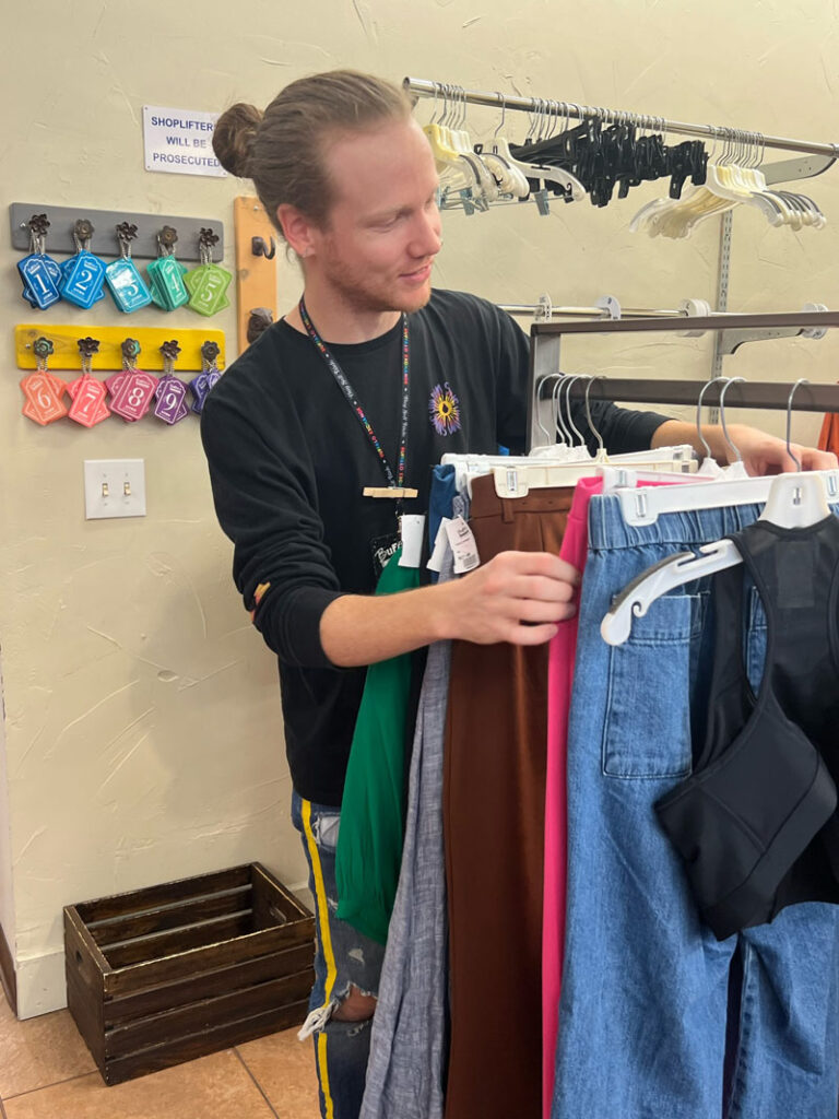 Buffalo Exchange employee looks at clothing on dressing room rack