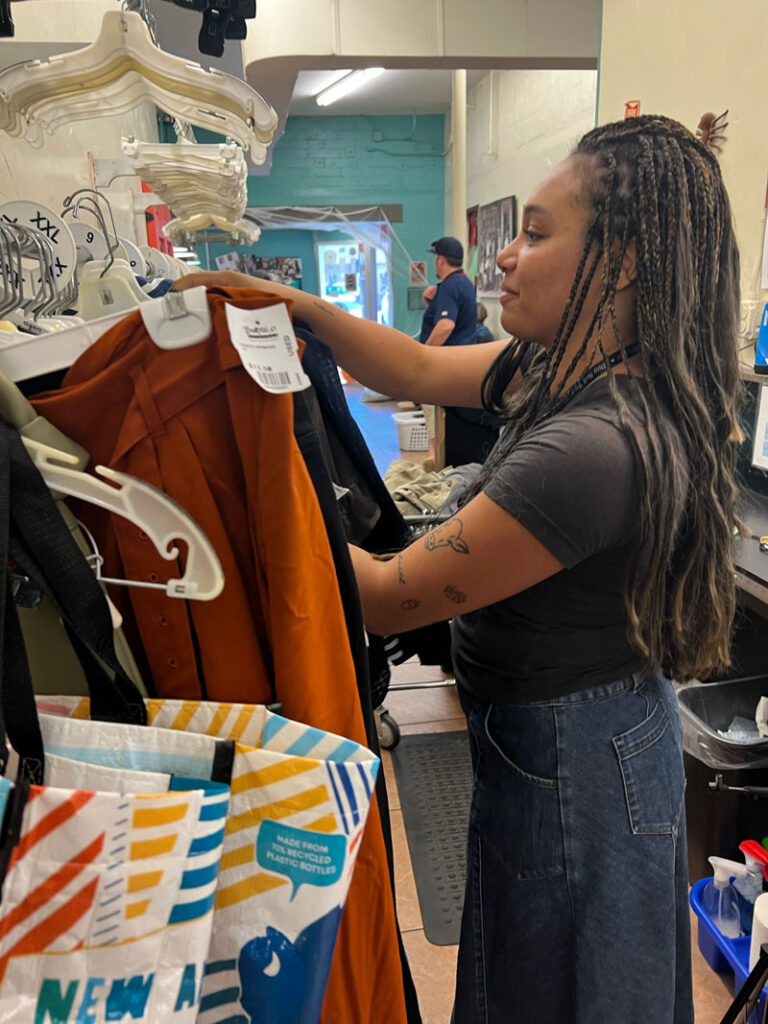 Buffalo Exchange employee hangs up clothing in the dressing room