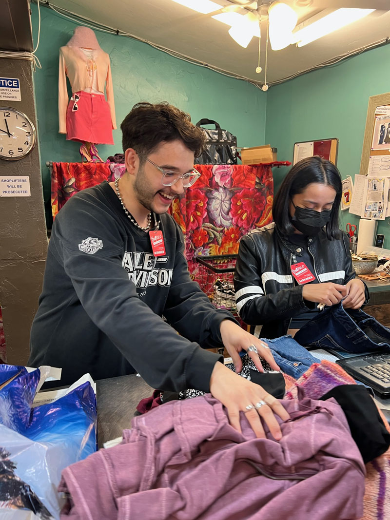 2 Buffalo Exchange employees evaluate clothing at the buy counter