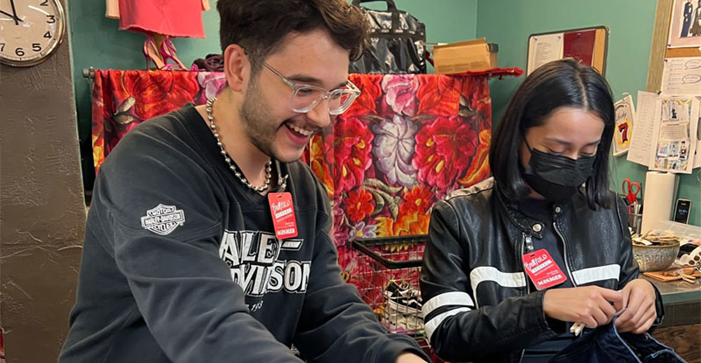 2 Buffalo Exchange employees evaluate clothing at the buy counter