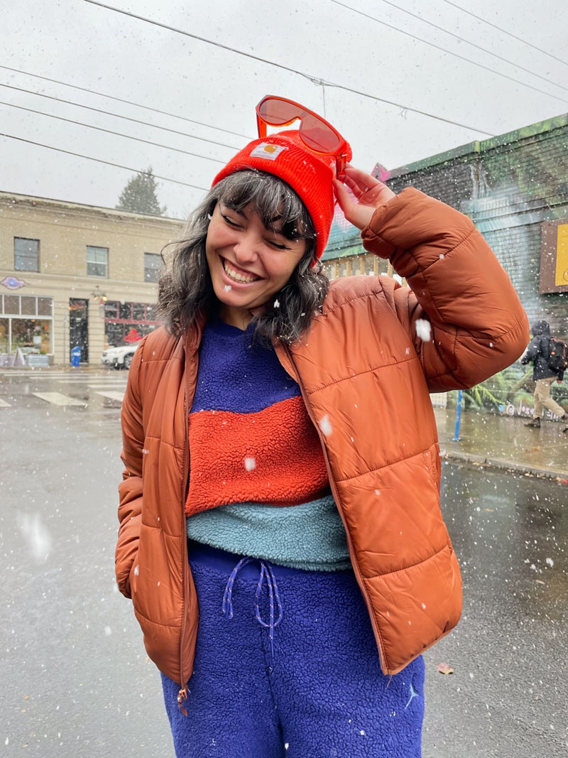person standing outside in a light snow wearing a burnt-orange puffer jacket and blue shearling set