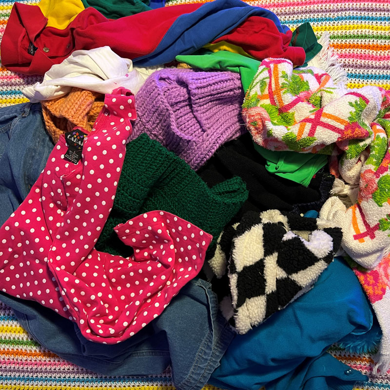 a bright, colorful pile of clothes strewn across a bed