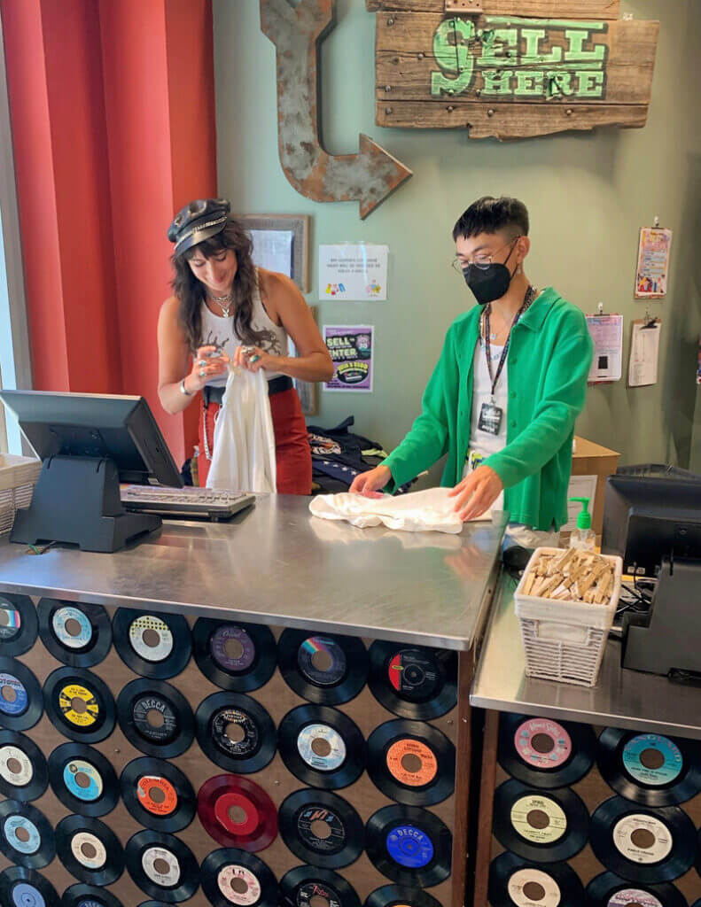 Two buyers processing clothes behind a buy counter.