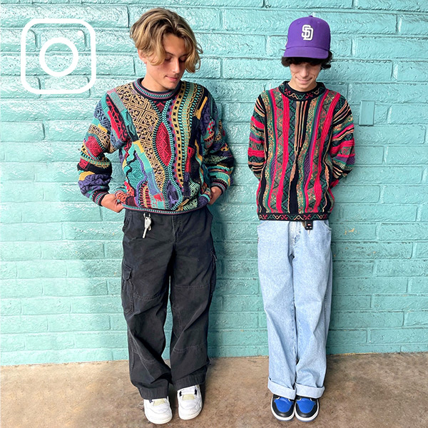 Two people wearing bright 90s inspired sweaters paired with jeans and sneakers. [Instagram logo]
