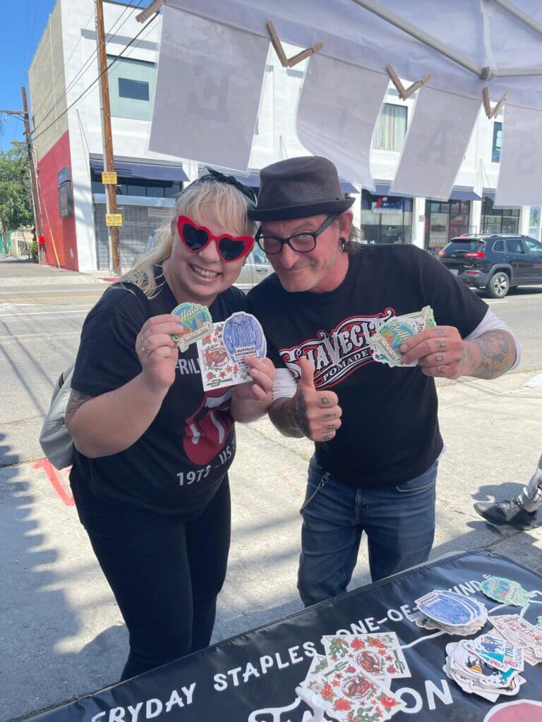 Two people holding Buffalo Exchange stickers