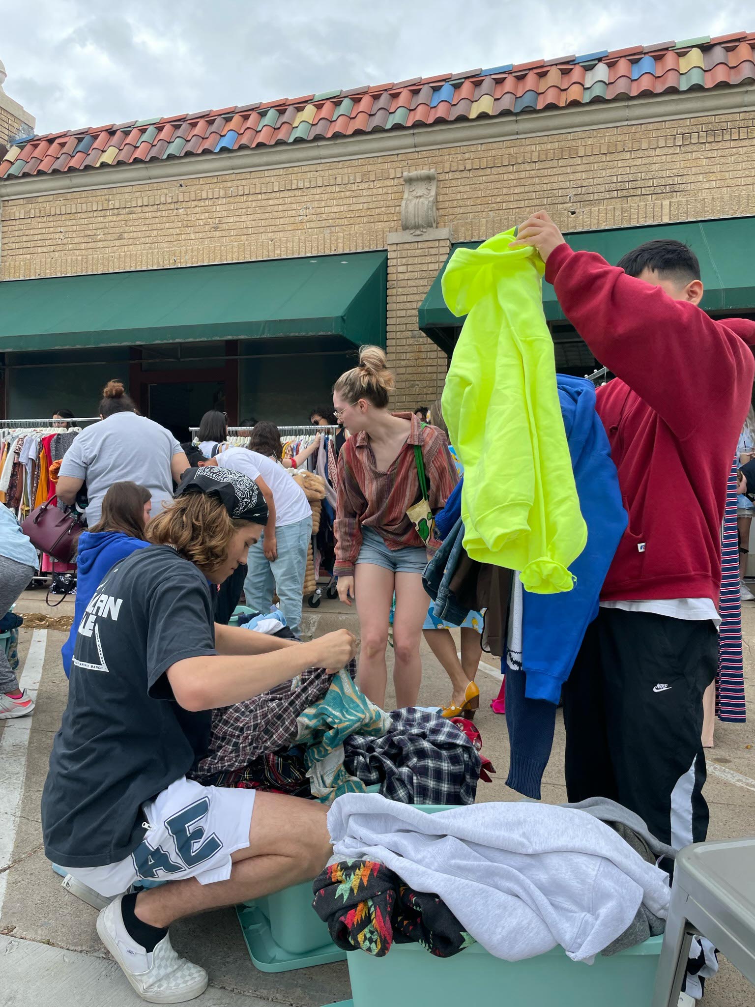 a group of people going through bins of clothes and shopping the $1 sale