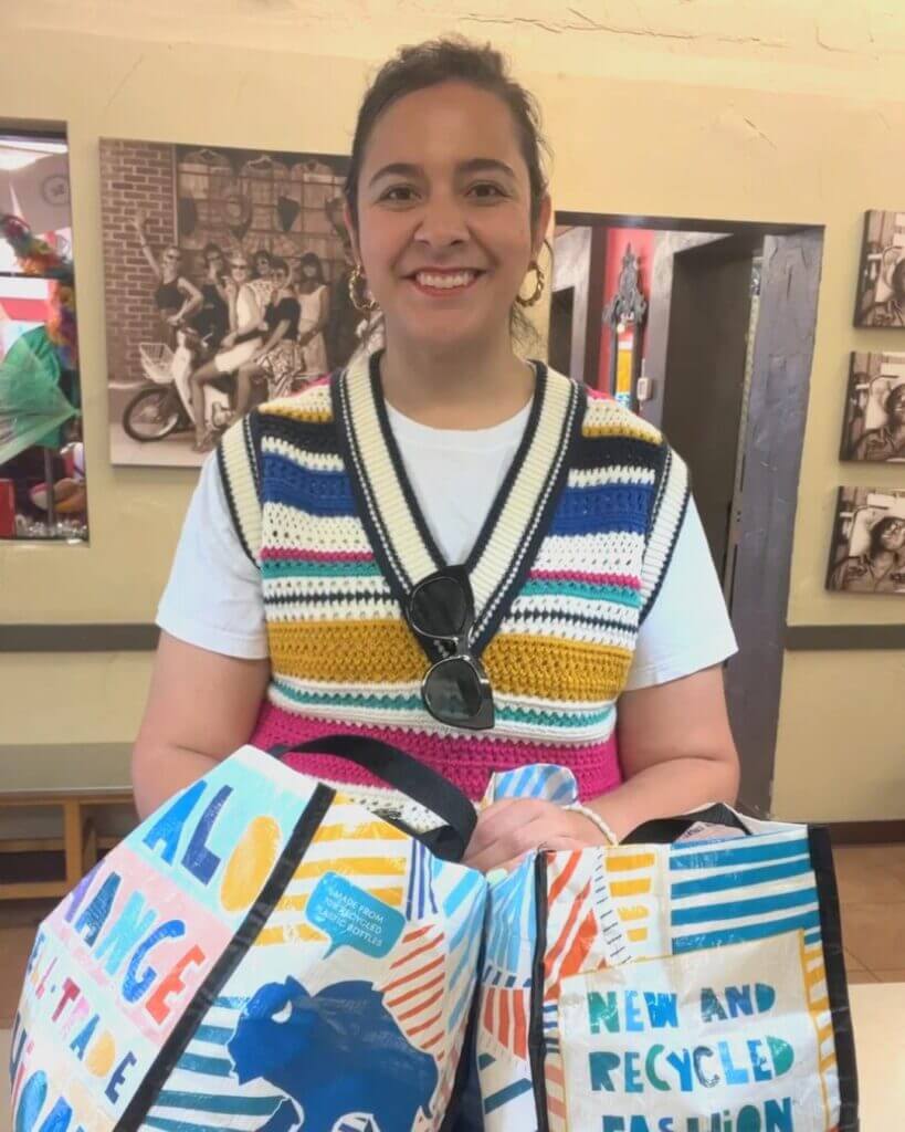 Customer holding two totes full of clothes at the buy counter