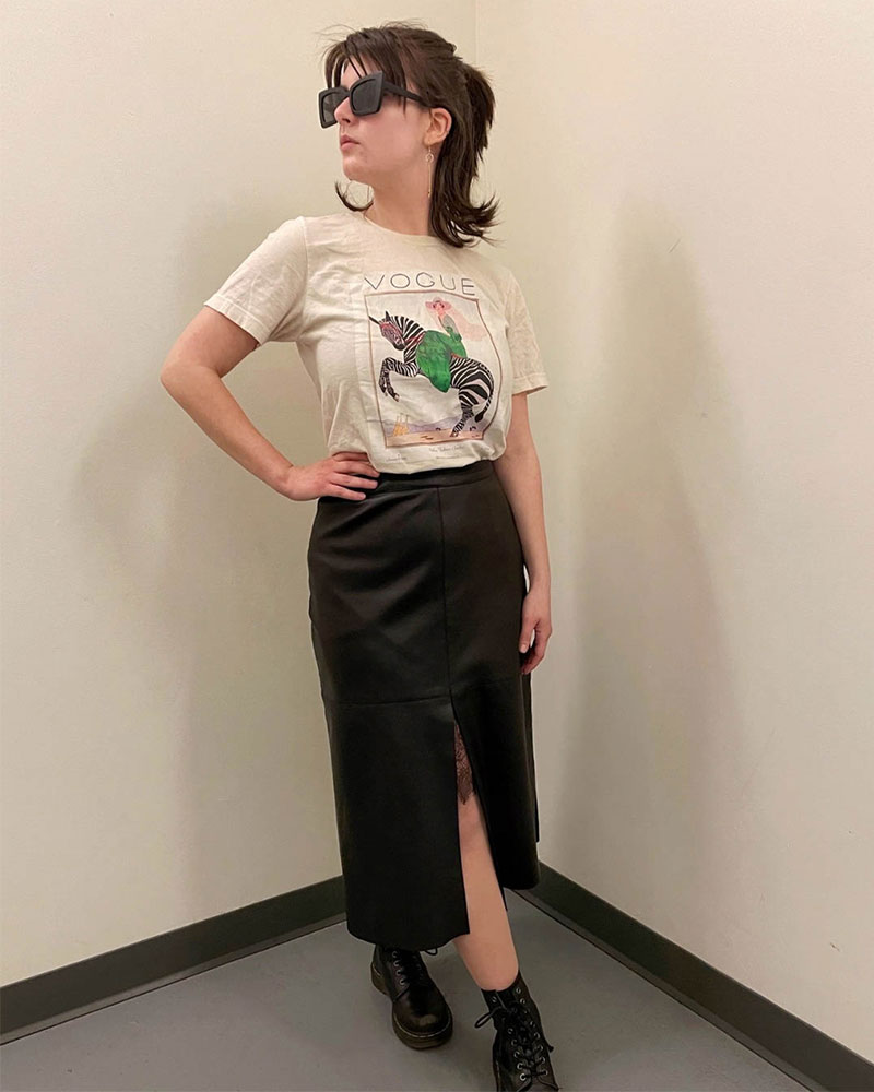 Person wearing black midi skirt paired with  'Vogue' t-shirt and black boots