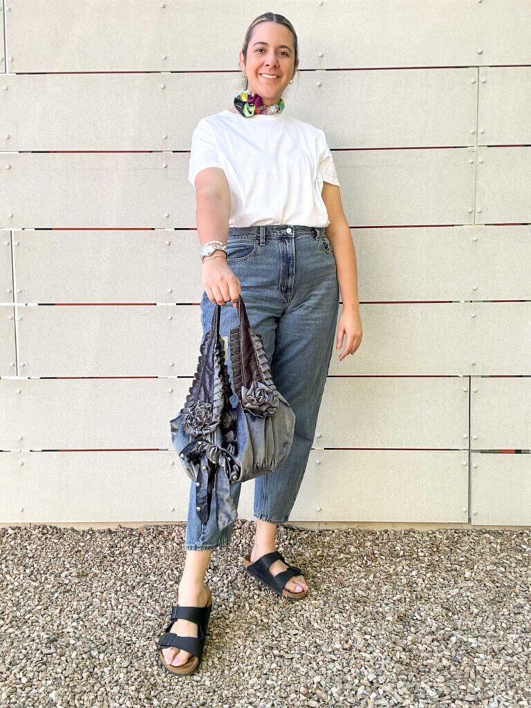 A woman posing in jeans and a white t-shirt with rose accessories