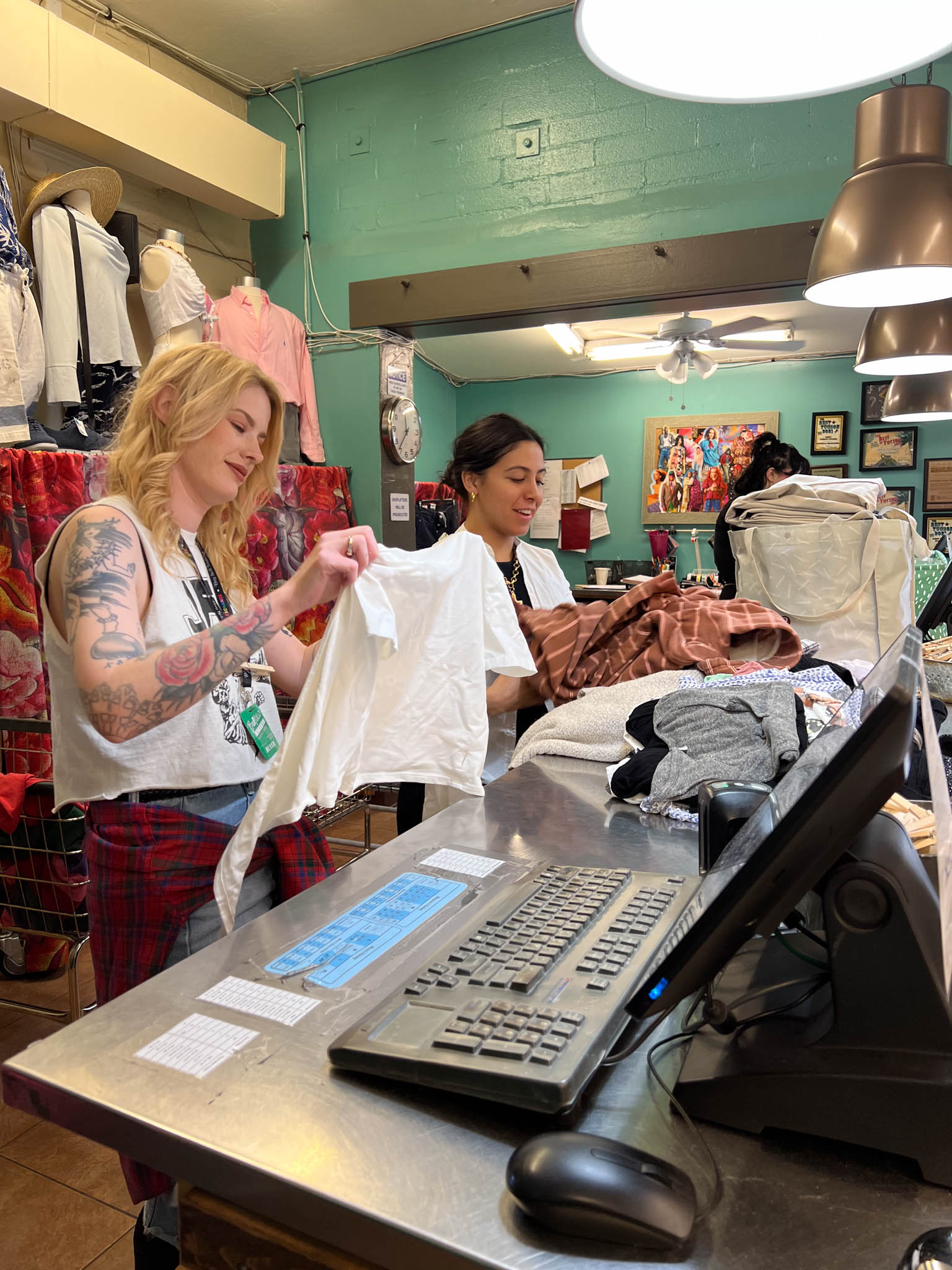 Two buyers sorting through clothes at the buy counter