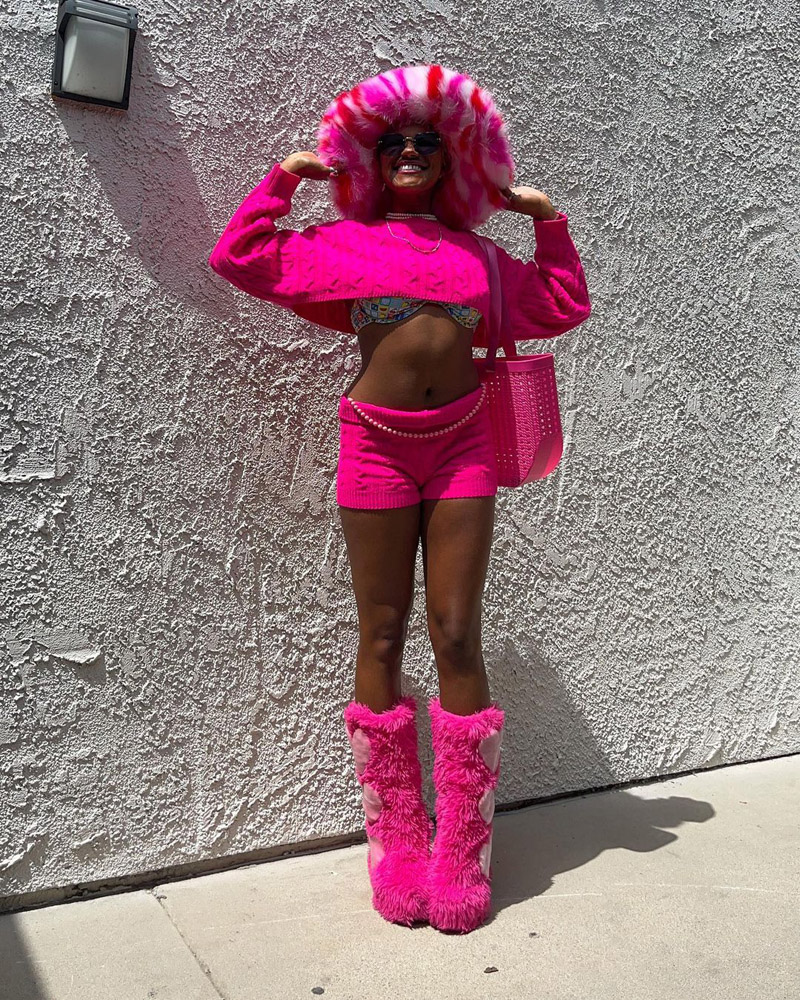 Customer @carlitalandrum wearing a hot pink Barbie-core look in a fuzzy hat and boots, cropped sweater, and matching knit shorts.