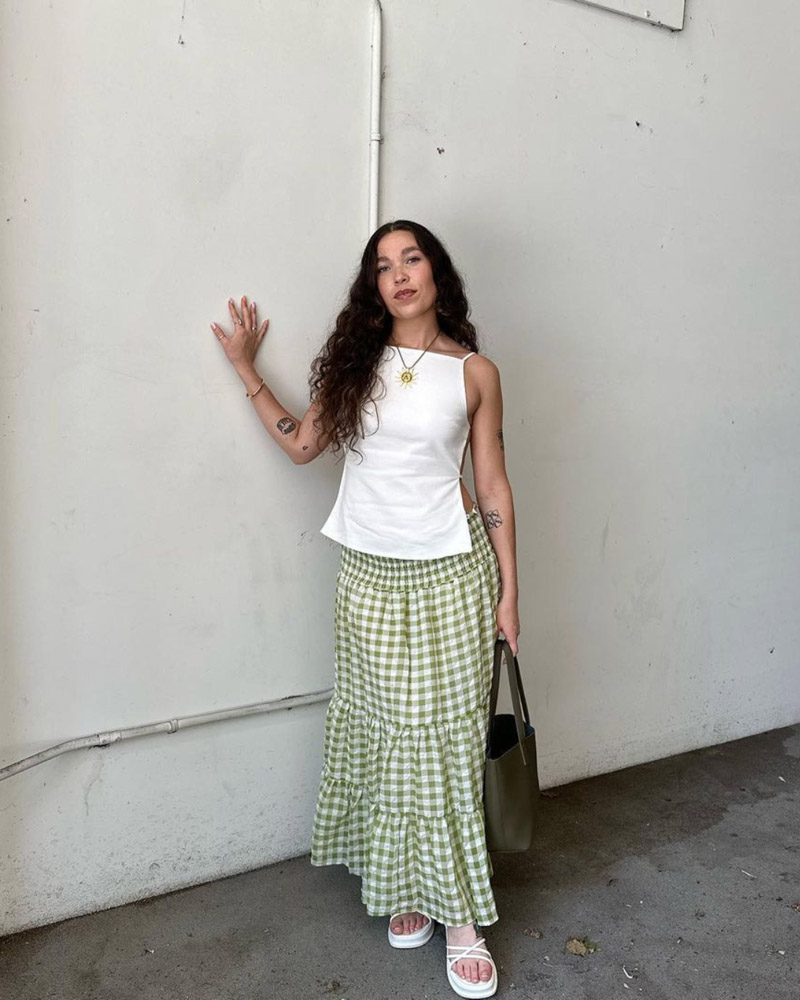 @danixelisa wearing a white tank top, green and white gingham maxi skirt, and white strappy sandals.