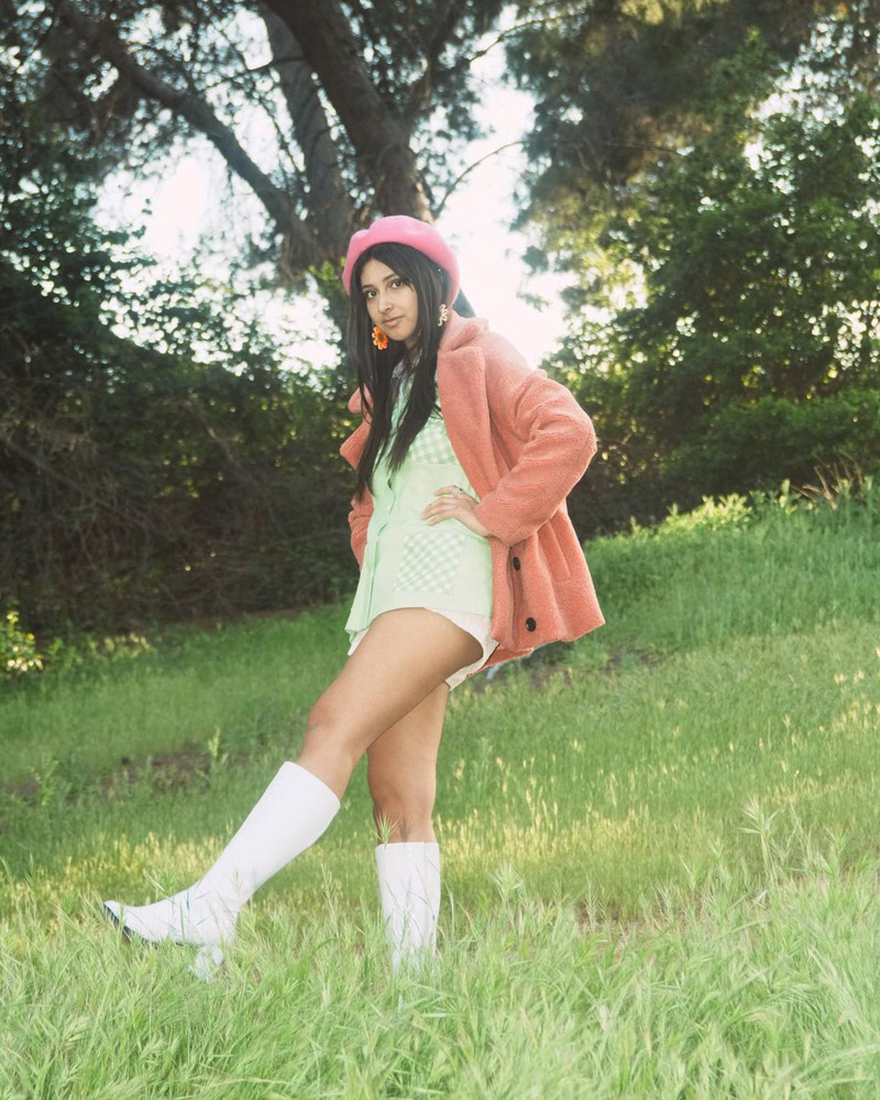 Customer @_sophiaagabriellee wearing a pink beret, a pink teddy coat over a light green button down shirt, and white knee-high boots.