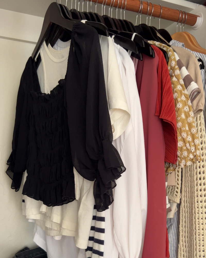 Clothes hanging in a closet, roughly in order by color