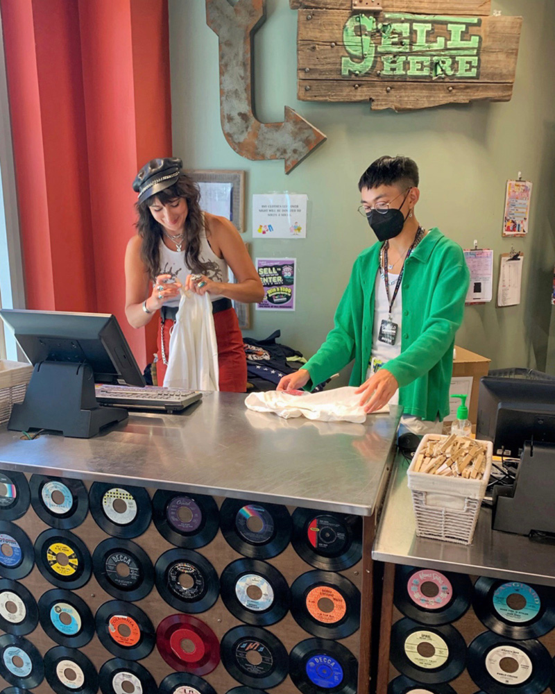 Two buyers processing clothes behind a buy counter.