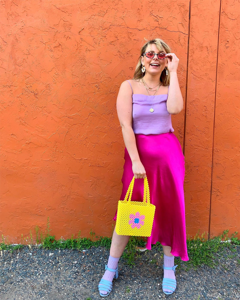 Person wearing Barbie costume with purple tank top, pink skirt and yellow daisy bag