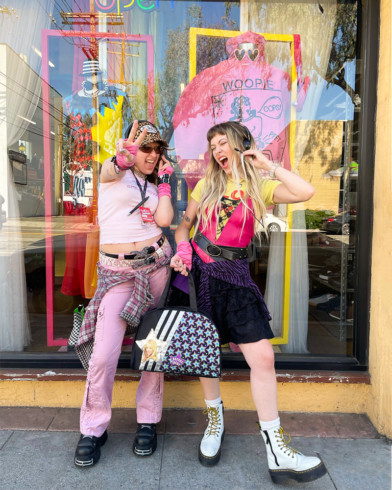 Two people dressed in Y2K-inspired outfits pose while wearing retro microphone headsets