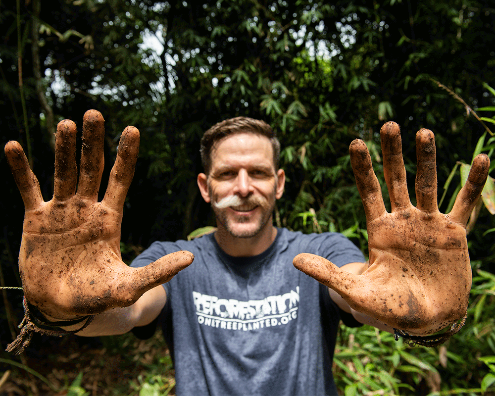 Man showing the palms of his hands covered in dirt 