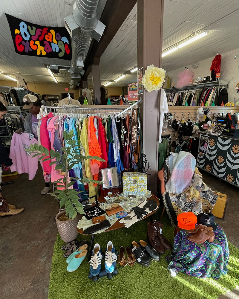 Boutique setup of vintage clothing with hand-knit Buffalo Exchange banner