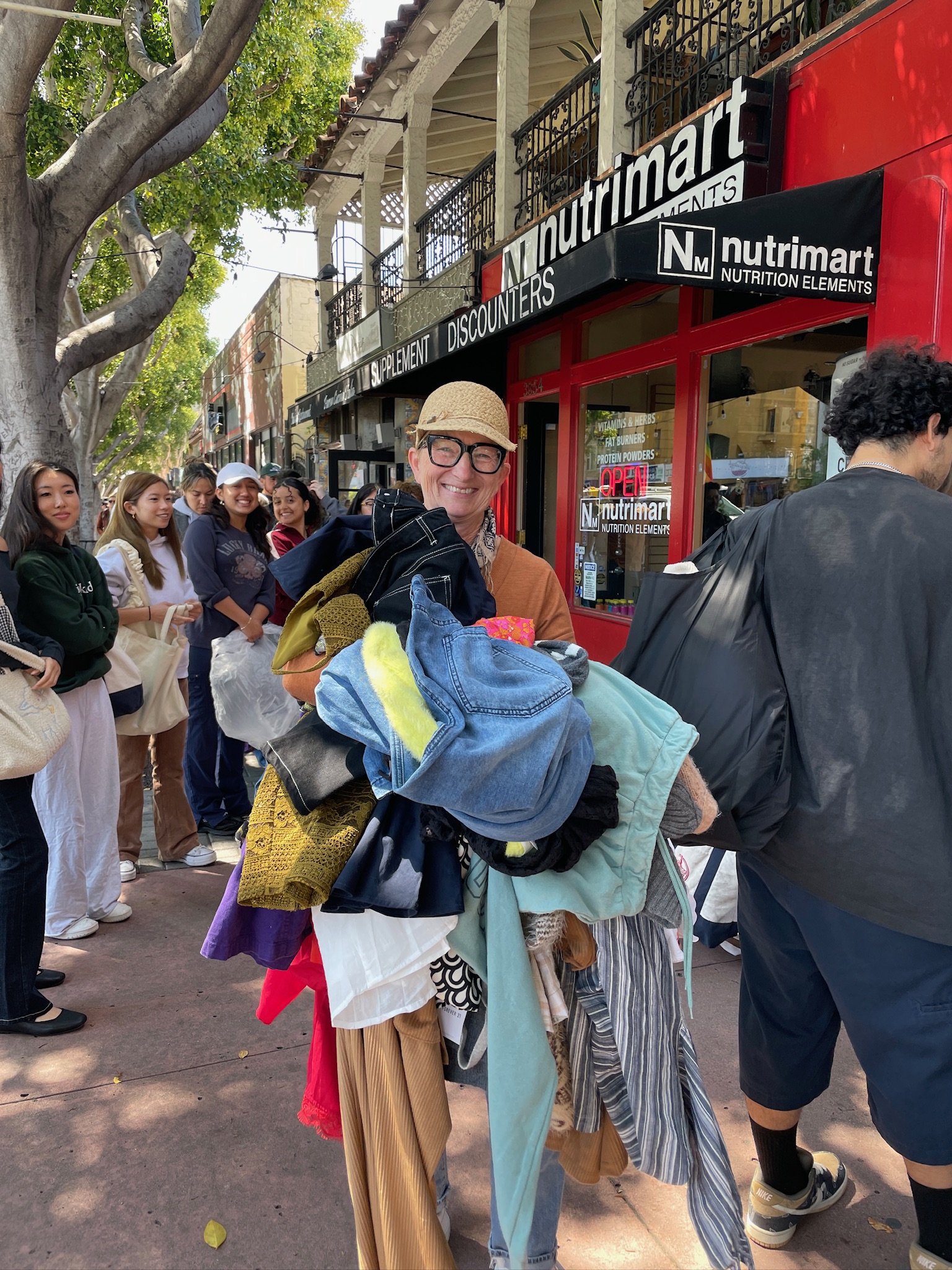 Customers holding pile of clothes at earth day dollar sale