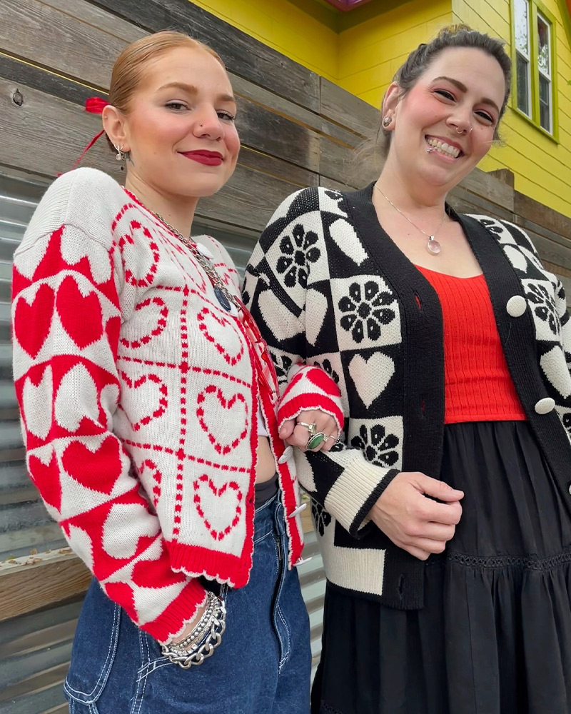 Two employees wearing matching heart pattern sweaters
