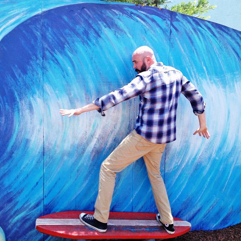 Joe pretending to surf in front of a painted wave