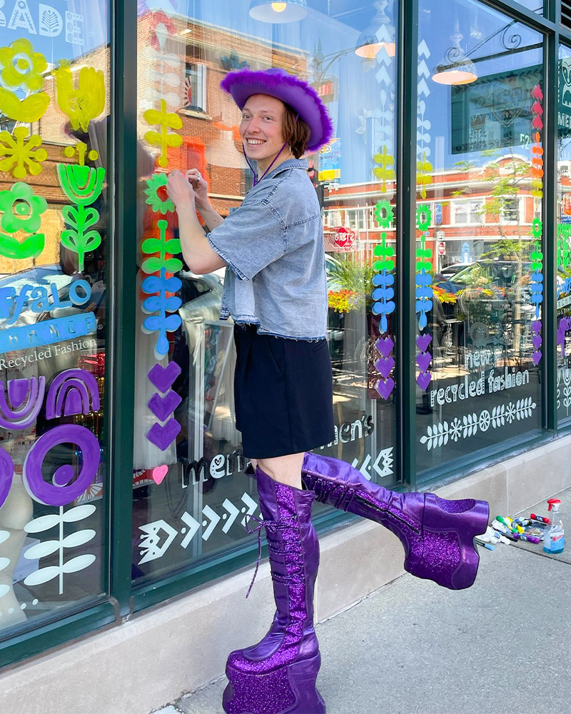 Buffalo employee sign painting in sparkly purple platform boots