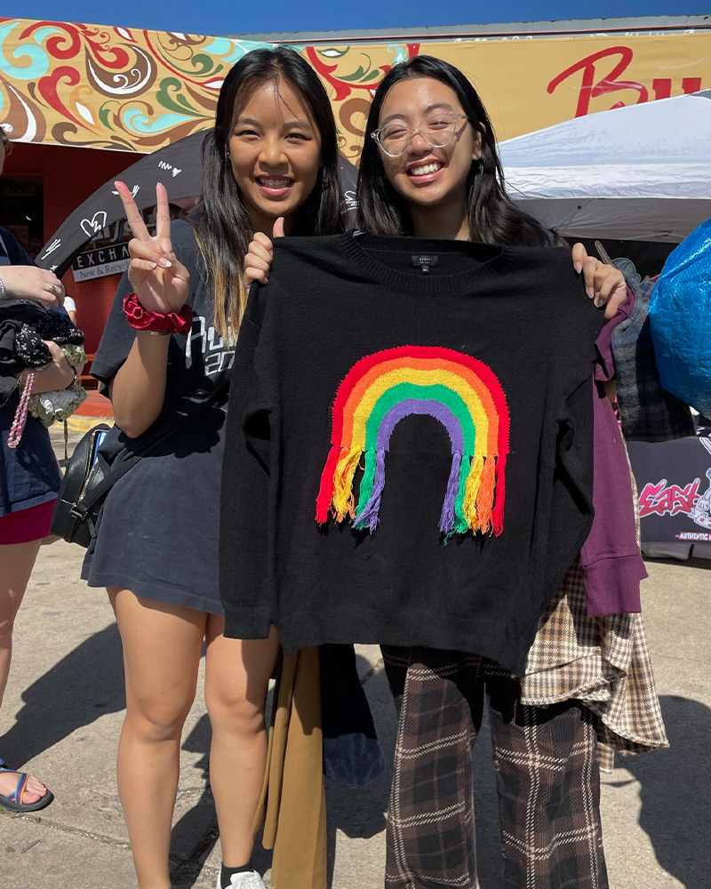 Two customers showing off a black hoodie with a rainbow detail