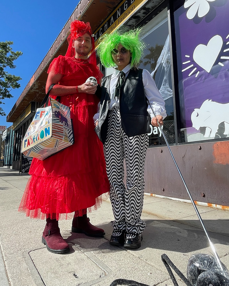 Halloween costumes of Lydia Deetz and Beetlejuice walking giant pet spider